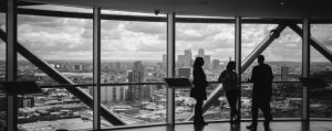 Group of three standing at window looking out onto a city landscape